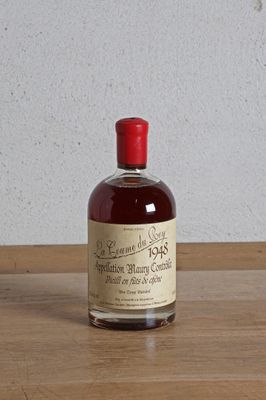 une bouteille d'alcool posée sur une table, avec un mur blanc en arrière-plan