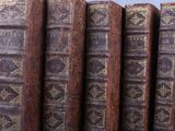Plusieurs vieux livres sont empilés les uns sur les autres, alignés en rangée.