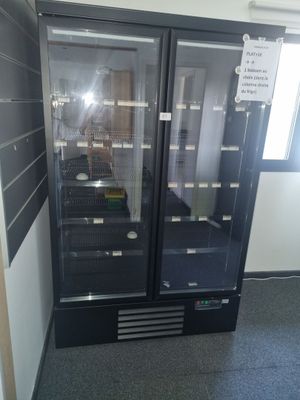 two refrigerators that are in a room with a sign on the wall