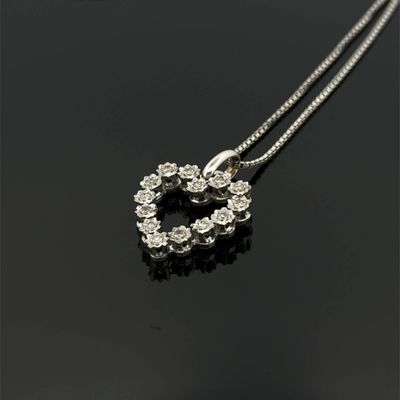 a heart shaped diamond pendant on a chain on a black surface