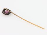 a close up of a gold stick with a purple stone on it