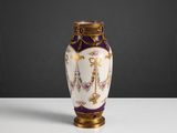 un vase violet et doré posé sur une table blanche, sur fond noir