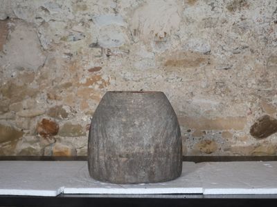 un vase en pierre posé sur une table devant un mur de briques