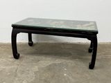 a black table with a glass top sitting on a cement floor