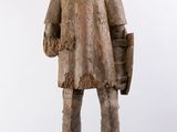 an old wooden statue of a boy with a hat and a bag
