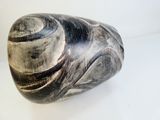 un vase noir et blanc posé sur une surface blanche