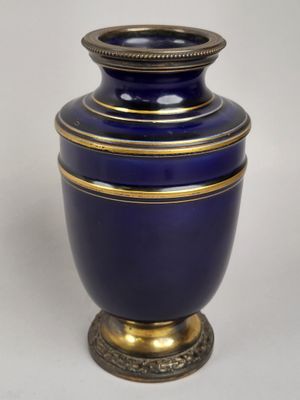 un vase bleu bordé d'or sur fond blanc