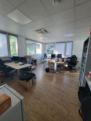 une salle où se trouvent de nombreux bureaux et chaises