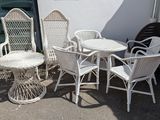 plusieurs chaises en osier blanc et une table à l'extérieur d'un bâtiment