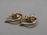 pair of gold tone earrings with clear crystal stones on a gray surface