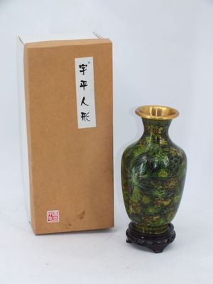 un vase vert posé à côté d'une boîte sur une surface blanche
