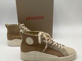une paire de baskets beiges avec des lacets blancs et une boîte