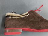 brown sued slippers with red soles on a gray surface