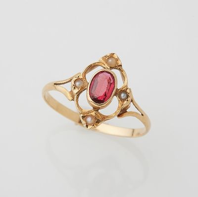 a gold ring with a red stone and pearls