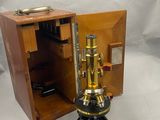 une petite boîte en bois contenant un microscope monté sur un trépied