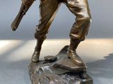 bronze statue of a soldier holding a rifle on a base