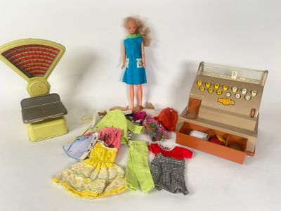 une poupée qui se tient à côté d'une boîte de vêtements