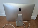 an apple computer sitting on a wooden floor with a charger attached to it