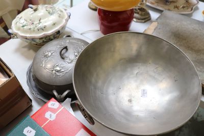 un grand saladier en métal posé sur une table, à côté d'autres objets