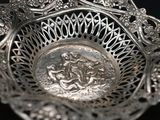 a silver bowl with a design on it on a black surface