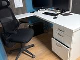 un bureau blanc avec une chaise noire et un ordinateur posé dessus
