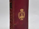 an old red book with a gold emblem on the cover