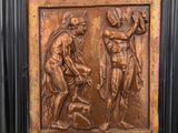 un relief en bronze représentant un homme et une femme, dans un cadre en bois