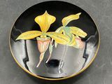 a black plate with a yellow flower painted on it