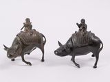 pair of bronze figurines of a man riding a boar and a man riding a pig