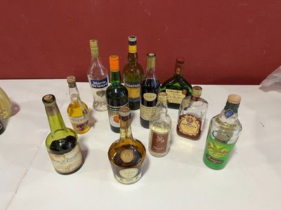 plusieurs bouteilles d'alcool posées sur une table, avec un mur rouge en arrière-plan