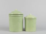 pair of green ceramic canisters with lids on a gray background
