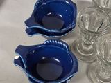 four blue dishes and two glasses on a white table