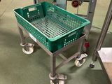 un panier vert posé sur un chariot métallique dans une usine