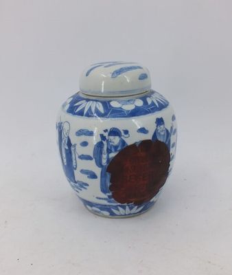 un petit pot bleu et blanc orné d'une fleur rouge