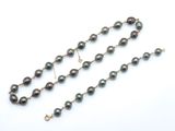 un gros plan d'un collier de perles noires posé sur une surface blanche