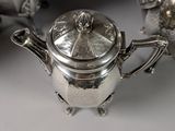 three silver teapots and a sugar bowl on a table