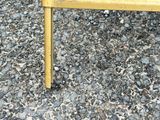 a yellow bench that is sitting on a gravel ground