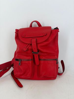 a red backpack with a tassel on it sitting on a white surface