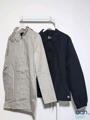 two jackets hanging on a clothes rack in a white room