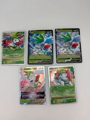 Quatre cartes Pokémon sont posées sur une table avec un fond blanc.