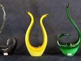 trois vases en verre de couleurs différentes posés les uns à côté des autres sur une surface noire