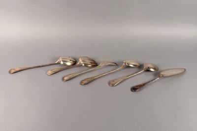 six cuillères en argent sont alignées sur une table