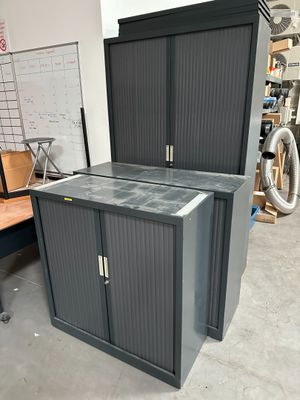 une armoire noire à deux portes, avec un vélo en arrière-plan