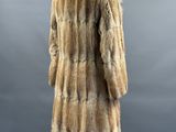 a fur coat on a mannequin stand against a gray background
