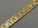 a close up of a gold bracelet on a gray surface