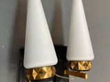 une paire de lampes blanches et dorées en forme de cône, fixées à un mur gris