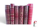 several old books are lined up in a row on a white surface