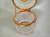 a glass toilet with a gold lid and chain around it