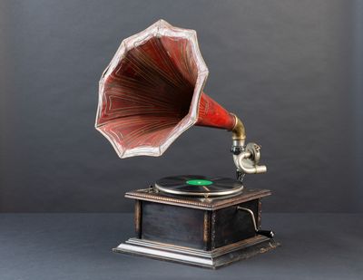 an old gramphone with a red horn on top of a wooden stand
