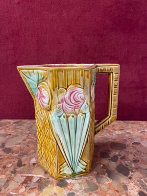a yellow pitcher with pink flowers on it on a table